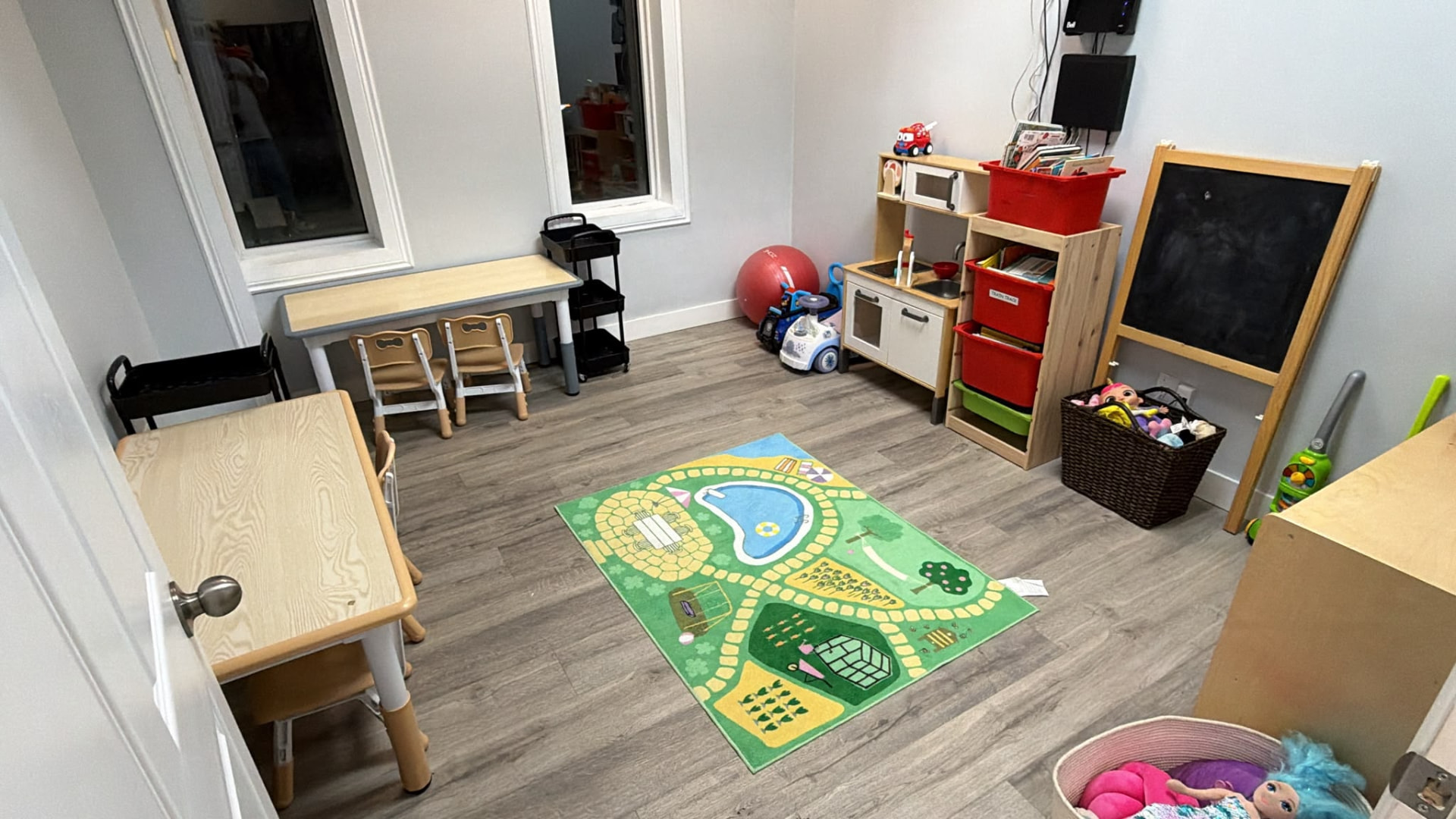 Play and learning room with child-sized tables, a toy kitchen and an activity rug