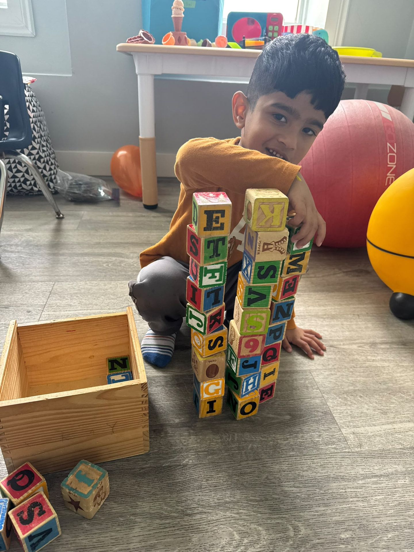 A child building a tall tower with colourful alphabet blocks