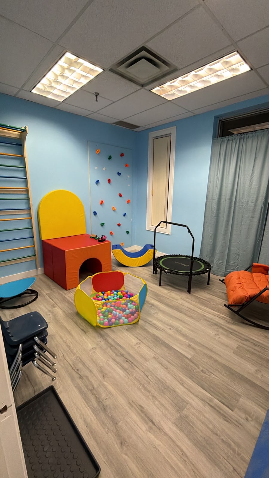 Blue activity room with a climbing wall, trampoline, soft equipment and a ball pit