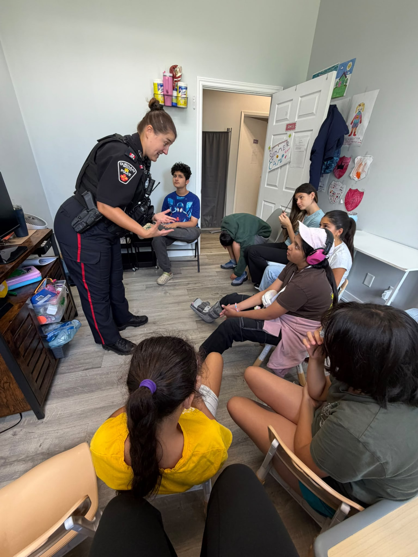 A police officer interacting with children and adults during an indoor visit