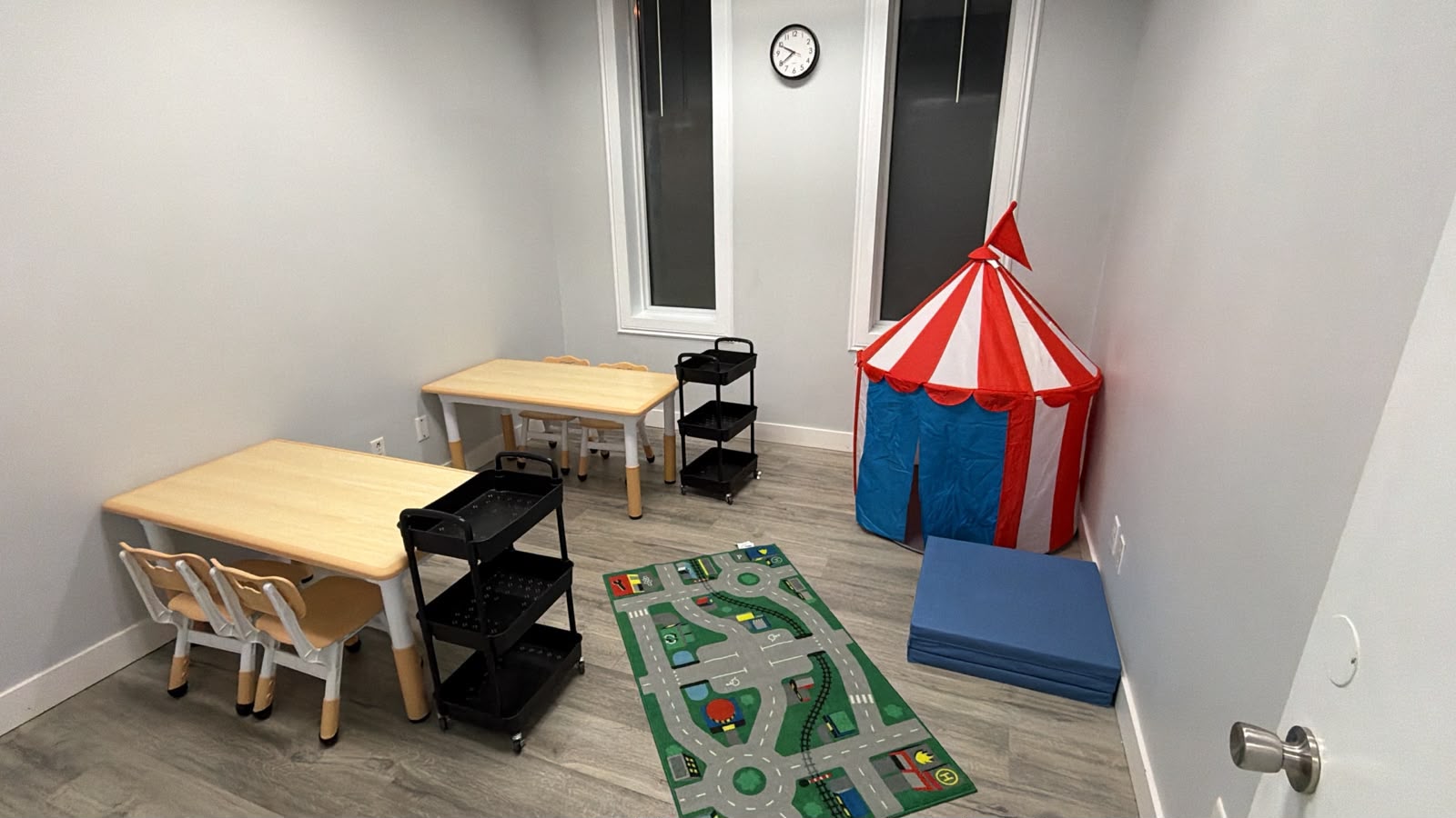 Learning room with two tables, a colourful play tent and floor mats