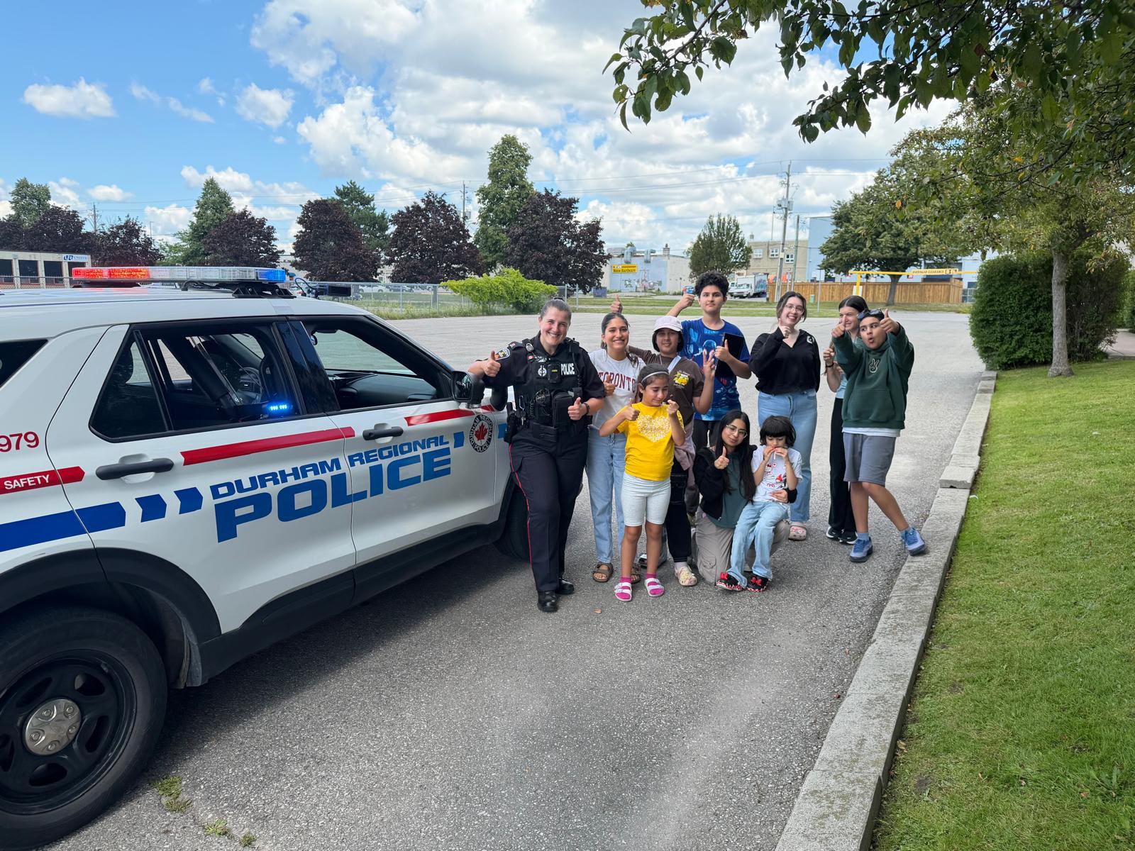 Children and adults beside a Durham Regional Police vehicle outdoors