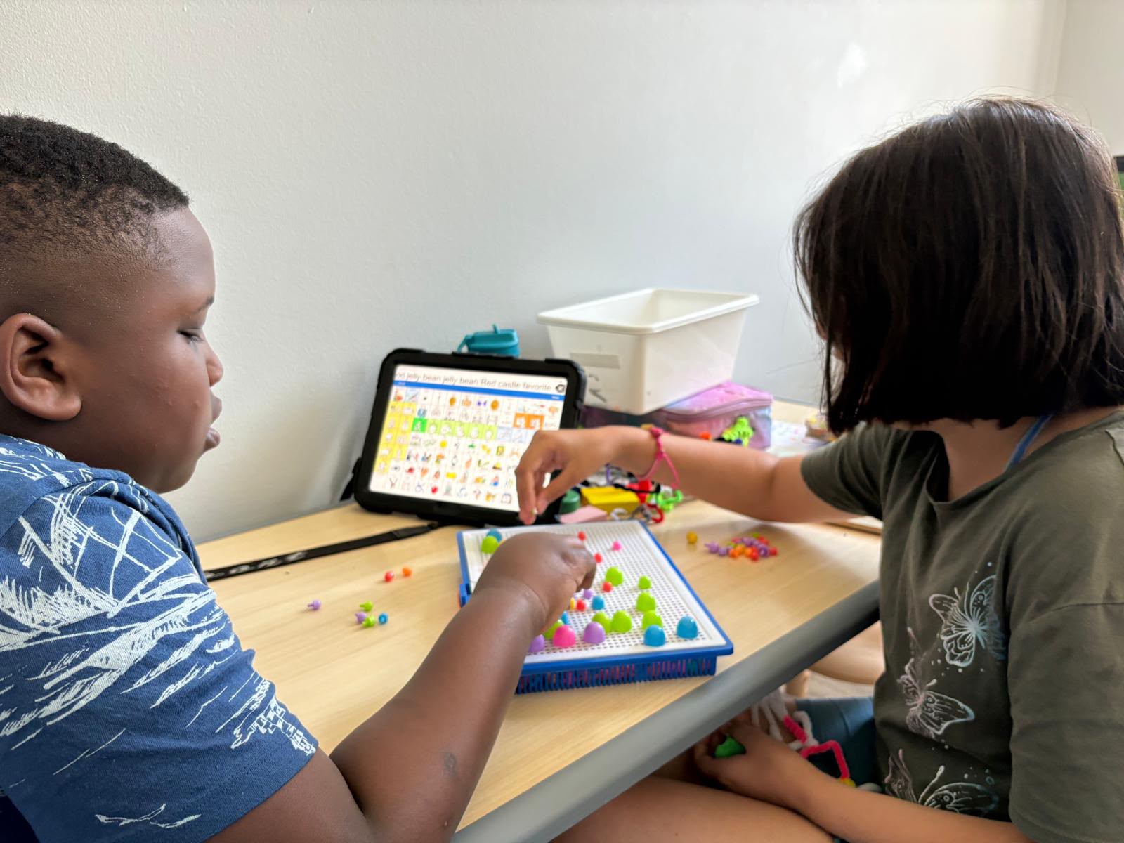 A child and an adult working together with learning materials at a table