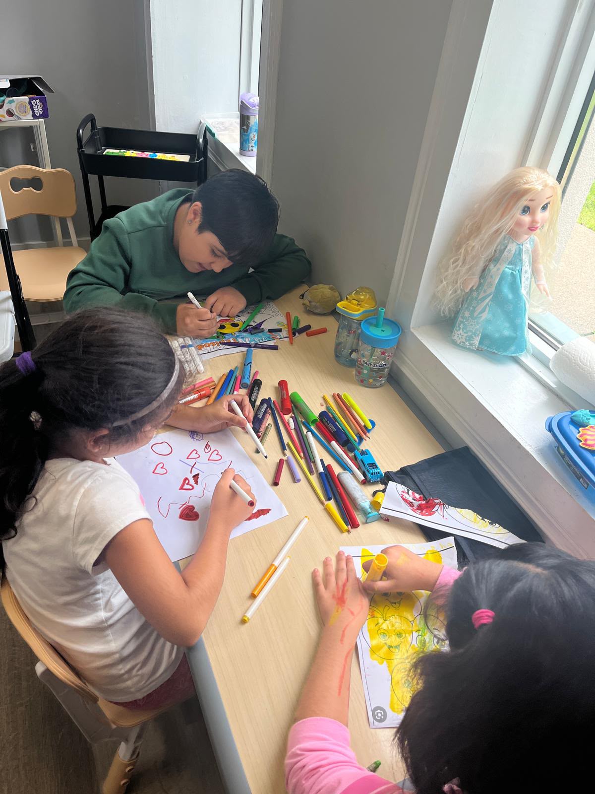 Children drawing and colouring together around a table